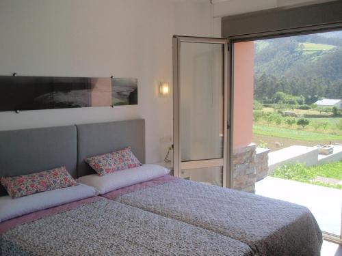 a bedroom with a large bed and a large window at Apartamentos Arcos del Esva in Luarca