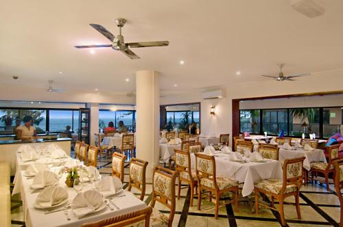 a restaurant with white tables and chairs and a ceiling fan at Clubb Coolum Beach Resort Sunshine Coast in Coolum Beach