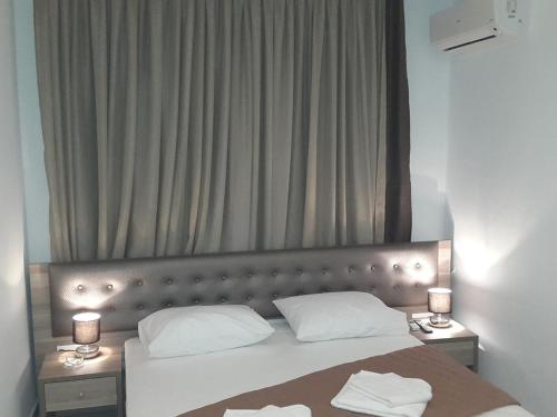 een slaapkamer met een bed met 2 nachtkastjes en 2 lampen bij Hotel Rex in Thessaloniki