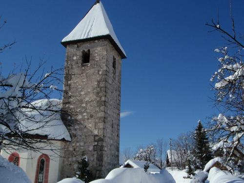 a tall stone tower with a snow covered roof at TEMPFER 2 Apartments & Rooms with new WELLNESS in Kranjska Gora