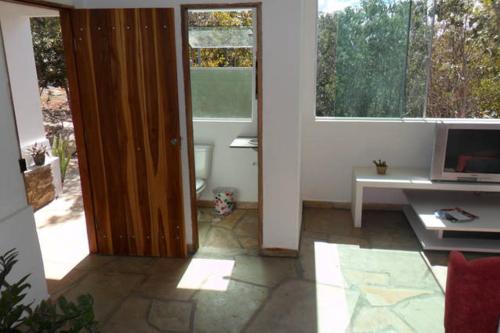 a room with a door leading to a living room with a desk and a computer at Morada dos Elfos in Vale do Capao