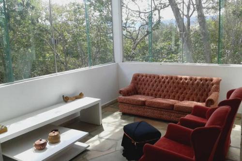 a living room with a couch and chairs and a large window at Morada dos Elfos in Vale do Capao