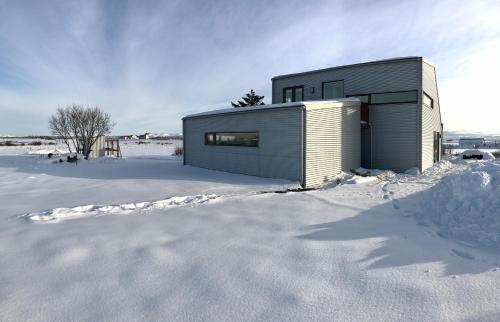 a house in the snow in the snow at Eyvindarholt Guesthouse in Álftanes