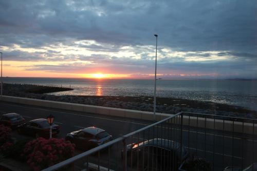 a sunset over the ocean with cars parked on a balcony at Shipping Lanes Hotel in Morecambe