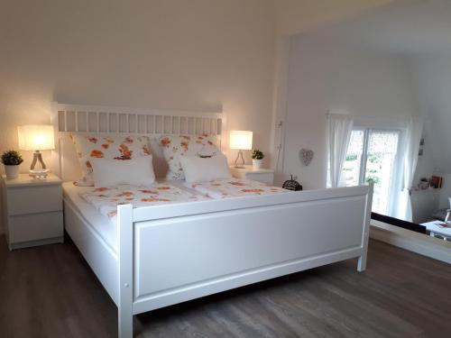 a white bed in a bedroom with two lamps at Ferienwohnung Weitblick in Wolfshagen