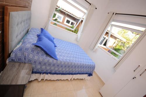 1 Schlafzimmer mit einem blauen Bett und 2 Fenstern in der Unterkunft Ecco House Buzios in Búzios