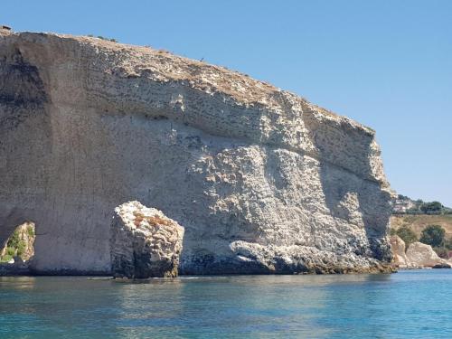 a large rock in the water next to a cliff at Cala Arenella in Sciacca