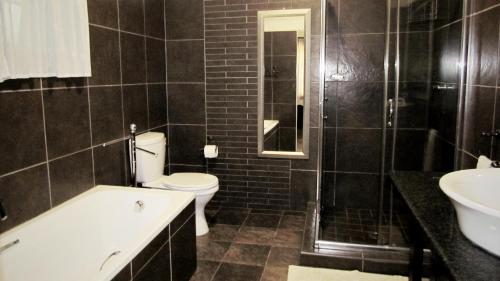 a black bathroom with a toilet and a sink at Duvet & Crumpets in Pietermaritzburg