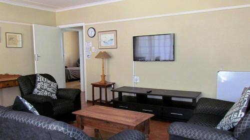 a living room with couches and a tv on the wall at Duvet & Crumpets in Pietermaritzburg