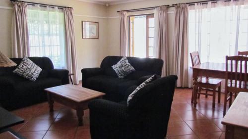 a living room with two chairs and a table and a dining room at Duvet & Crumpets in Pietermaritzburg