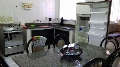 a kitchen with a table with chairs and a refrigerator at Apartamento em Piúma-ES in Piúma