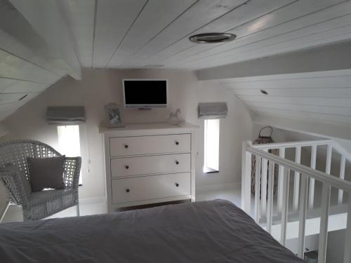 1 dormitorio con cama y vestidor con TV en B&B 't Hoveke, en Wingene
