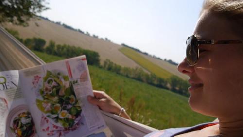 a woman reading a magazine in a field at Tenuta Tredici Ulivi in Senigallia