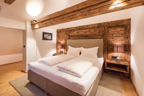 1 dormitorio con 1 cama grande y pared de madera en Pepi's Landhaus, en Schattwald