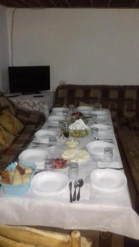 a long table with plates and utensils on it at Guesthouse Dritan Tethorja in Theth