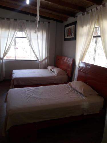 two beds in a room with two windows at Bungalows Rupay Wasi in Los Órganos