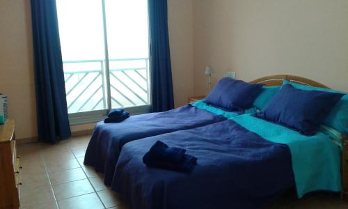 a bedroom with a bed with blue sheets and a window at Duplex Apartment in La Tejita in La Mareta