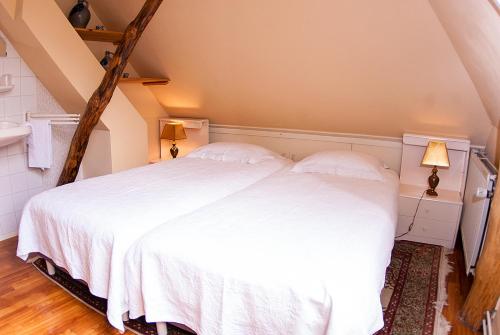 a bedroom with a white bed in a attic at B&B De Oude Molensteen in Eelde-Paterswolde