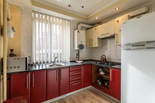 a kitchen with red cabinets and a white refrigerator at Apartment in the city center in Dnipro