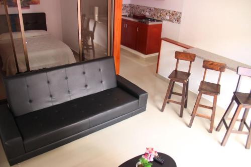 ein Wohnzimmer mit einem schwarzen Sofa und einigen Stühlen in der Unterkunft Apartahotel Calle del tiempo detenido in Filandia