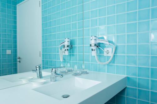 Praia de Santos, Exclusive Villa, Açores في بونتا ديلغادا: حمام من البلاط الأزرق مع حوض ومرآة