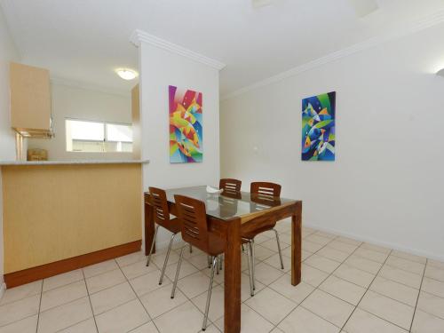 a dining room with a table and chairs and paintings at Central Plaza Port Douglas in Port Douglas