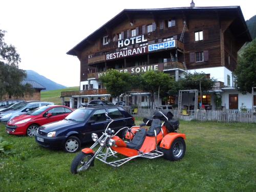 a motorcycle parked in the grass in front of a hotel at Hotel Restaurant Walliser Sonne in Reckingen - Gluringen