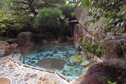 una fuente termal en un jardín con rocas en Ryokan Adumaya en Hongu