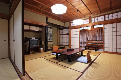 a living room with a table and a tv at Ryokan Adumaya in Hongu