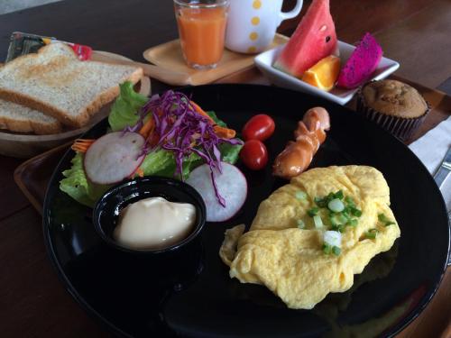 a black plate of food with an omelet and a salad at The Wishes Hotel at Chiangmai in Chiang Mai
