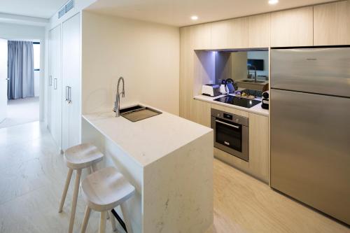 a kitchen with a counter and a sink and a refrigerator at Breeze Mooloolaba, Ascend Hotel Collection in Mooloolaba