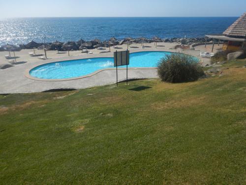 a swimming pool with chairs and the ocean in the background at Departamento Puerto Velero in Puerto Velero