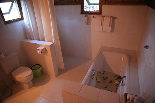 a white bathroom with a tub and a toilet at Golden Island Cottages Nampan in Ywama