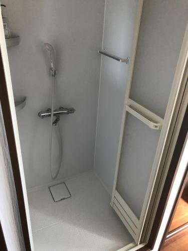 uma casa de banho com um chuveiro e uma porta de vidro em Palette Takashimadaira guest house em Tóquio