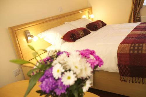 a bed with a white bedspread and flowers on it at Gateway Hotel in Newport