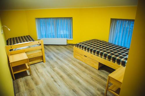 two beds in a room with yellow walls and wooden floors at Alina Hotel & Hostel in Uzhhorod