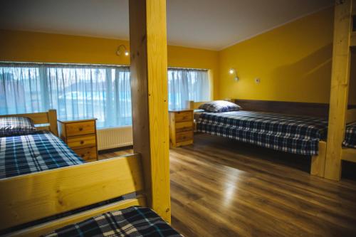 two beds in a room with yellow walls and wooden floors at Alina Hotel & Hostel in Uzhhorod