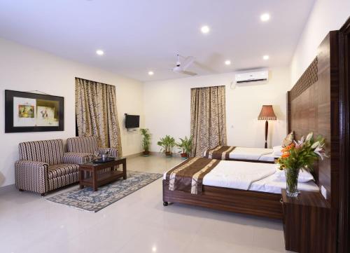 ein Schlafzimmer mit einem Bett, einem Sofa und einem Stuhl in der Unterkunft Chowdhury's Guest House in Kalkutta