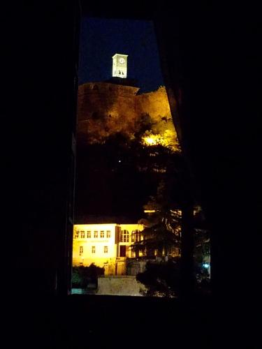 a building with a clock tower at night at Lori's traditional house in Gjirokastër