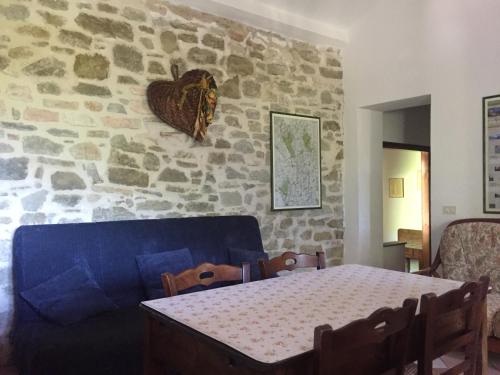 a living room with a blue couch and a stone wall at Casale degli ulivi in Gualdo Tadino