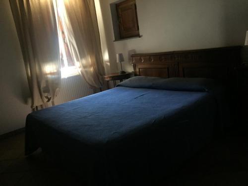 a bedroom with a bed with a blue blanket and a window at Casale degli ulivi in Gualdo Tadino
