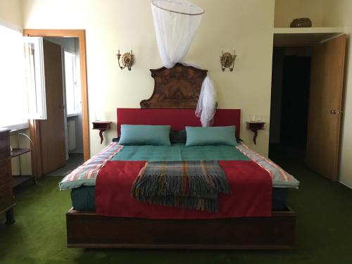 a bedroom with a large bed with a red headboard at La Casa Blu di Monasteto in Tricesimo