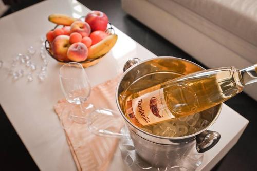 a bottle of champagne in a bucket on a table with a bowl of fruit at Sokoterme Hotel in Soko Banja