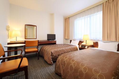 a hotel room with two beds and a desk at Hotel Grand Plaza Urashima in Kurihara