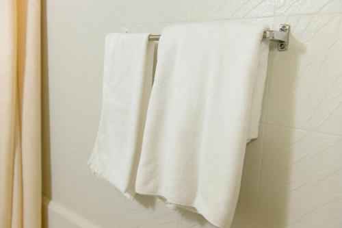 two white towels hanging on a towel rack in a bathroom at Hotel Grand Plaza Urashima in Kurihara