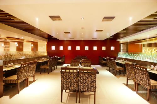 a restaurant with tables and chairs and red walls at Hotel Sitara Grand L.B. Nagar in Hyderabad