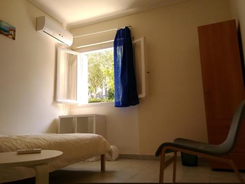 アテネにあるArtemidos Apartmentのベッドルーム1室(ベッド1台付)、青いカーテン付きの窓が備わります。