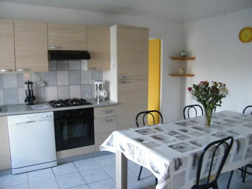 a kitchen with a table with a white table cloth at Les Charmois - Spa privatif en supplément et sur un autre site in Bains-les-Bains