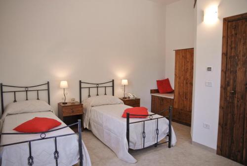 a bedroom with two beds with red pillows at Masseria Valente in Ostuni