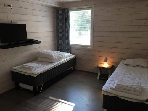 a room with two beds and a tv and a window at Willa Pihlaja in Punkaharju